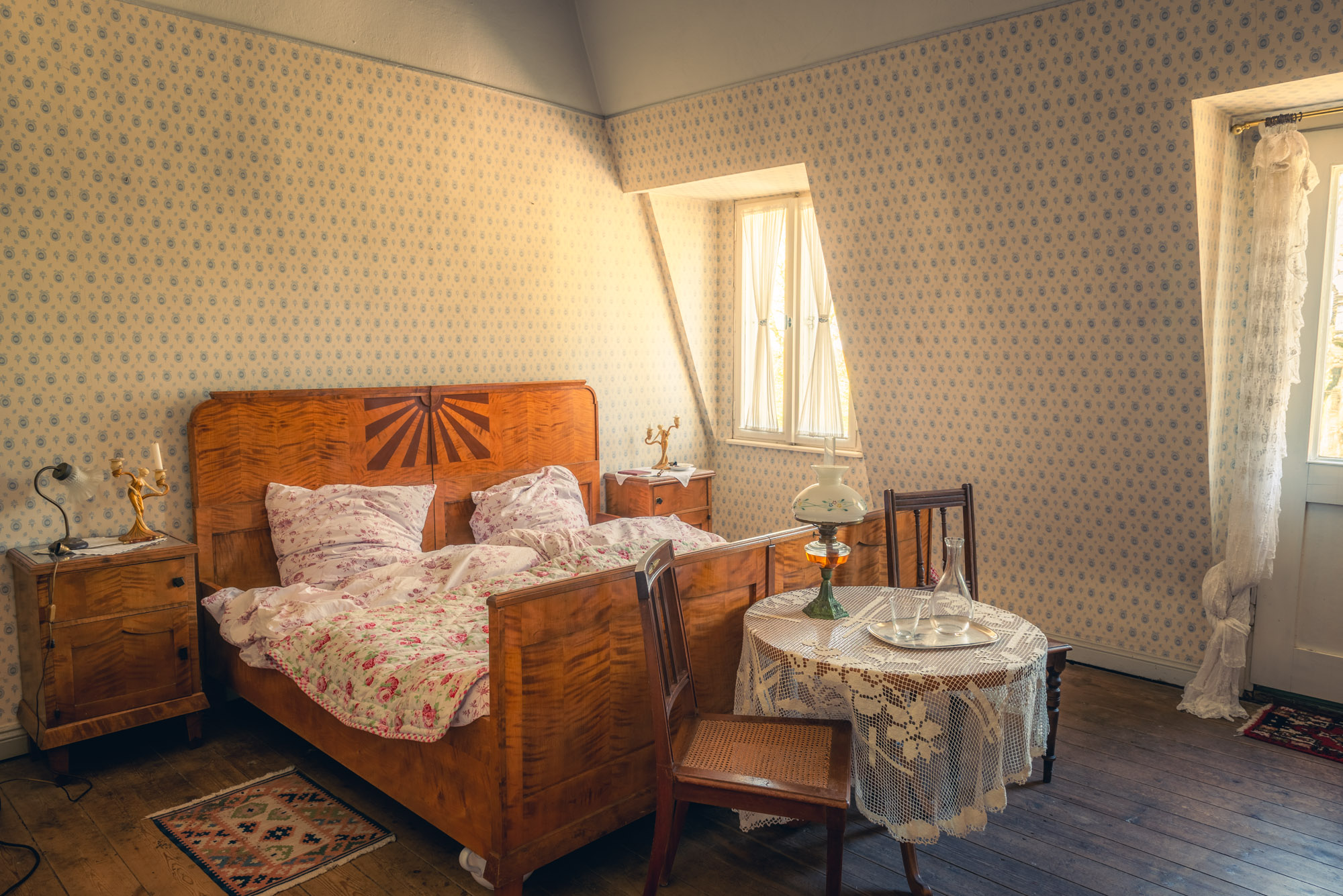 Kitschig eingerichtetes Doppelzimmer mit Blumenbettwäsche. Historische Hochzeitssuite.