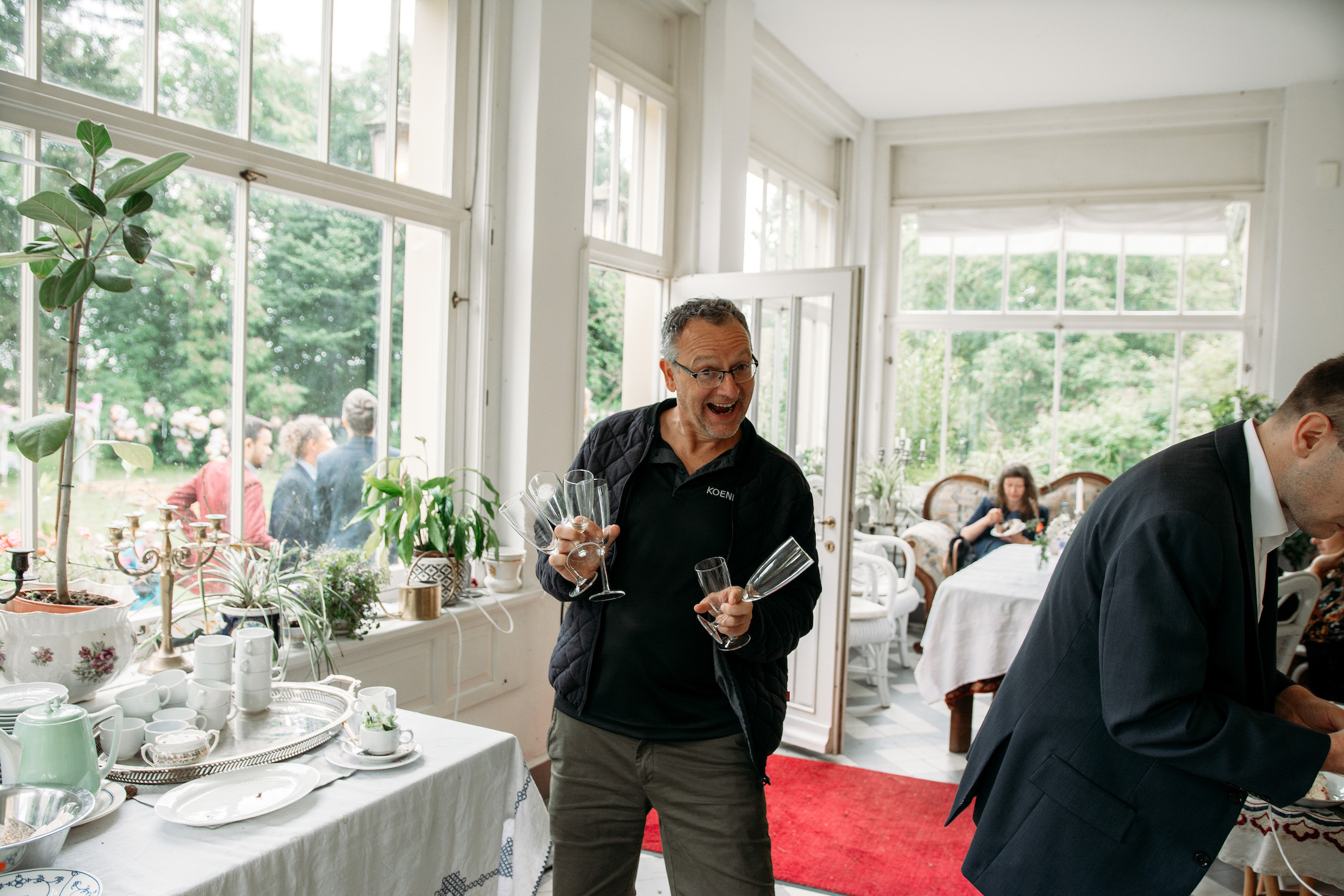 Mann mit Sektgläsern in Wintergarten.